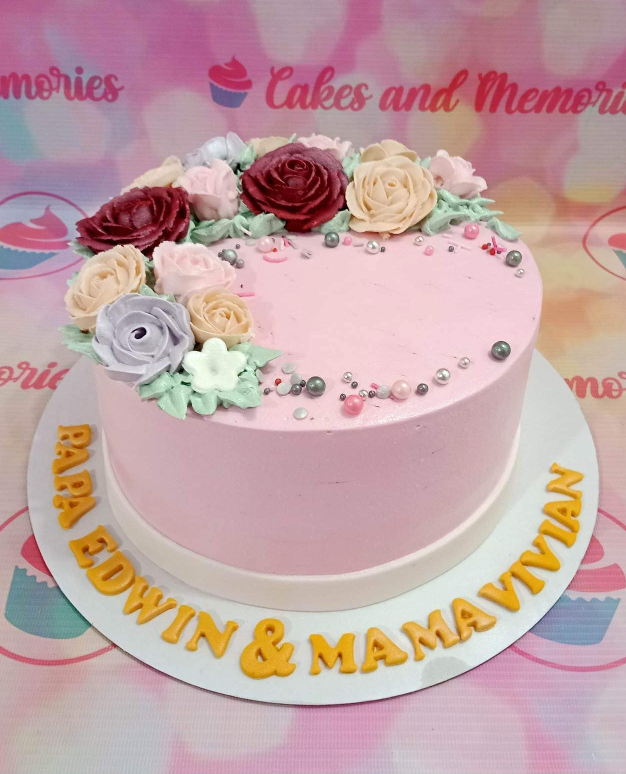 Pink floral cake with edible gumpaste roses in burgundy, peach, and lavender, decorated with silver and pink dragees. Pink floral cake with edible gumpaste roses in burgundy, peach, and lavender, decorated with silver and pink dragees.