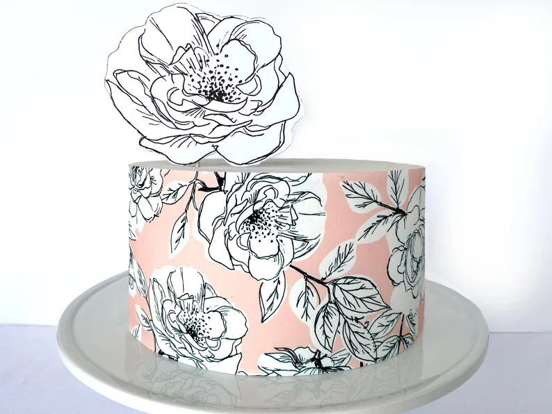 Single tier pink cake with black and white floral print and a large matching flower topper. Single tier pink cake with black and white floral print and a large matching flower topper.