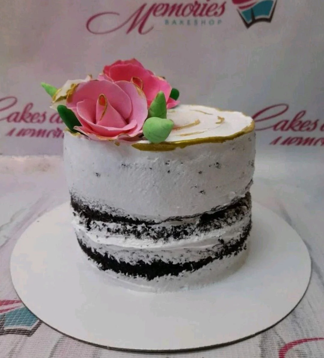 Single tier chocolate semi-naked cake with pink gumpaste roses and gold painted rim on top.