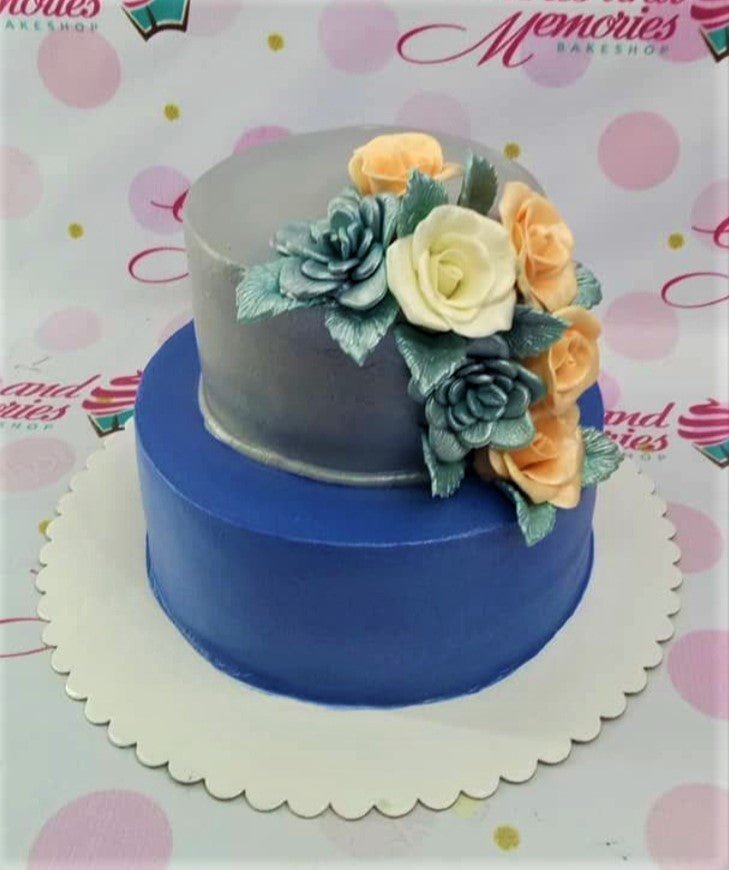 Elegant two-tier cake with a silver-gray top tier and a deep blue bottom tier, adorned with peach and teal gumpaste roses. Elegant two-tier cake with a silver-gray top tier and a deep blue bottom tier, adorned with peach and teal gumpaste roses.
