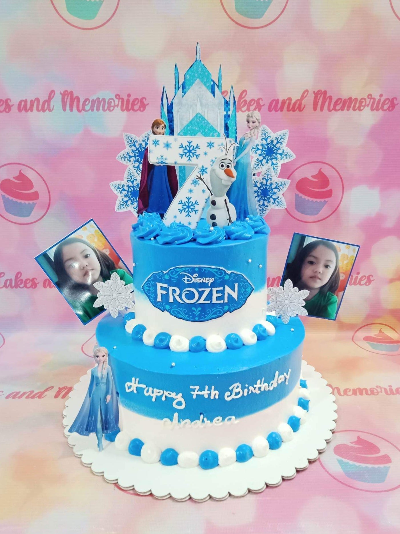 Two-tier Frozen themed birthday cake in blue and white with Elsa, Anna, and Olaf toppers and personal photos. Two-tier Frozen themed birthday cake in blue and white with Elsa, Anna, and Olaf toppers and personal photos.