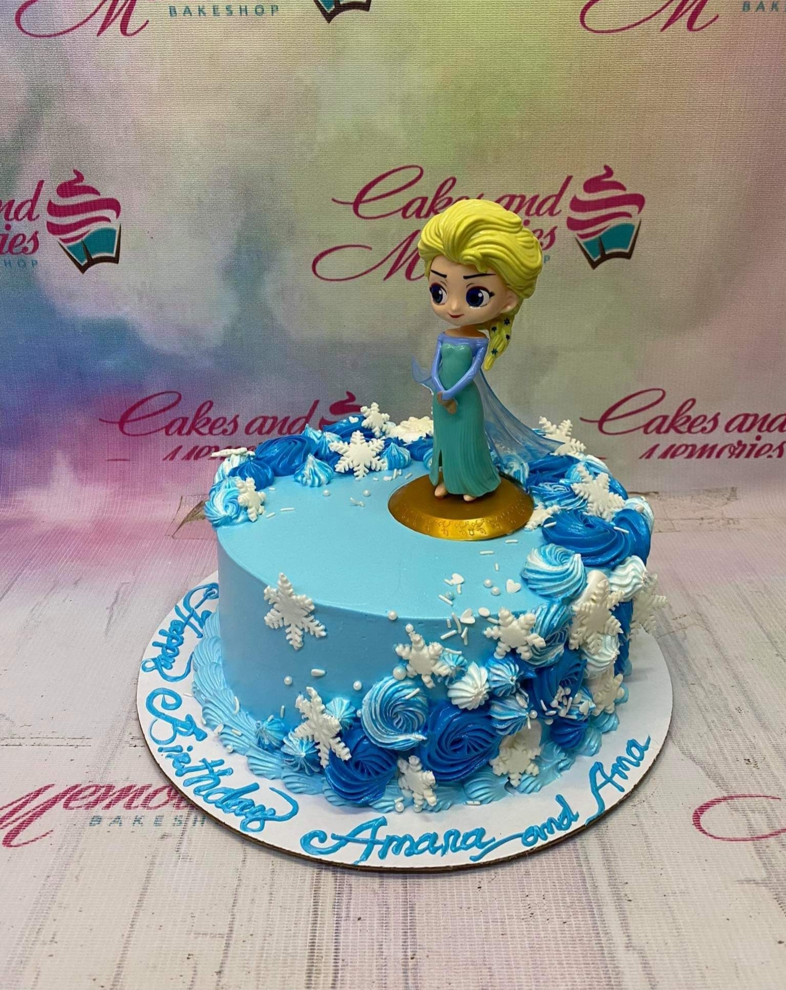 Light blue Frozen themed birthday cake with Elsa figurine, white snowflakes, and blue icing rosettes. Light blue Frozen themed birthday cake with Elsa figurine, white snowflakes, and blue icing rosettes.