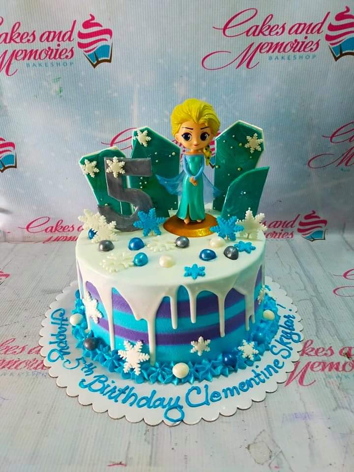 Frozen themed Elsa birthday cake with blue and purple striped icing, white drip, and a 3D Elsa figurine on top. Frozen themed Elsa birthday cake with blue and purple striped icing, white drip, and a 3D Elsa figurine on top.