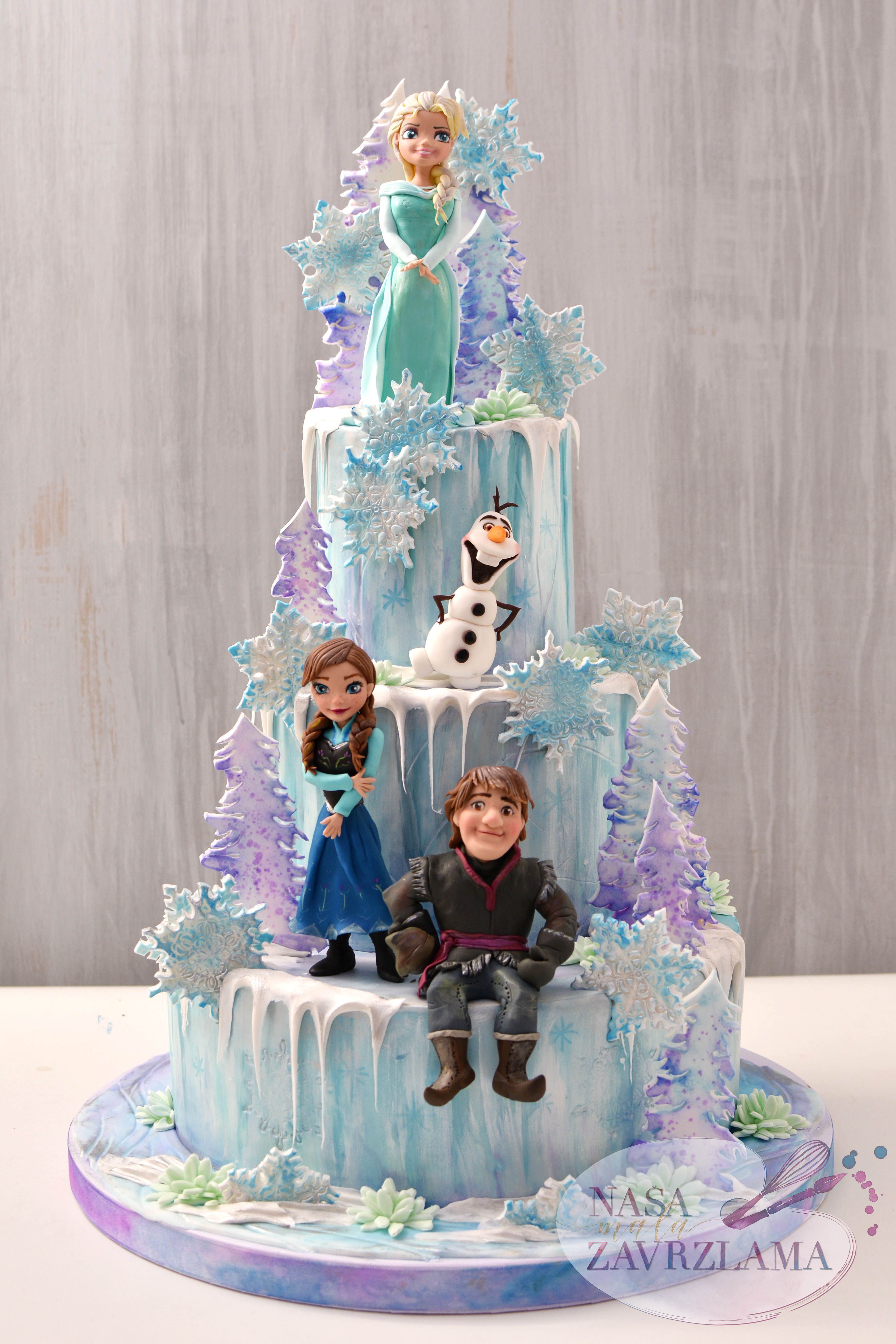 Three-tier Frozen themed cake featuring Elsa, Anna, Kristoff, and Olaf figurines with edible snowflakes and purple pine trees. Three-tier Frozen themed cake featuring Elsa, Anna, Kristoff, and Olaf figurines with edible snowflakes and purple pine trees.
