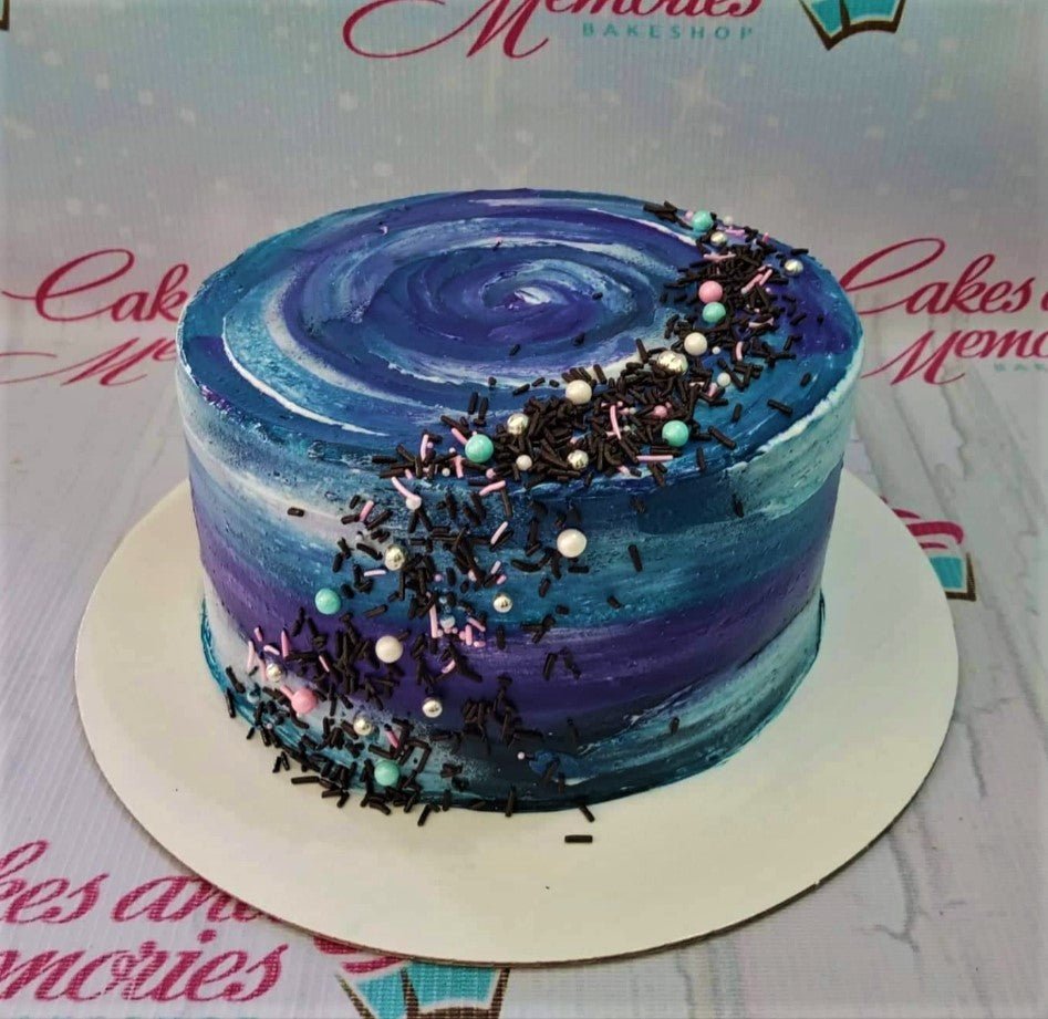 Single tier cake with a blue and purple galaxy swirl icing design and a crescent of chocolate sprinkles and colorful pearls. Single tier cake with a blue and purple galaxy swirl icing design and a crescent of chocolate sprinkles and colorful pearls.