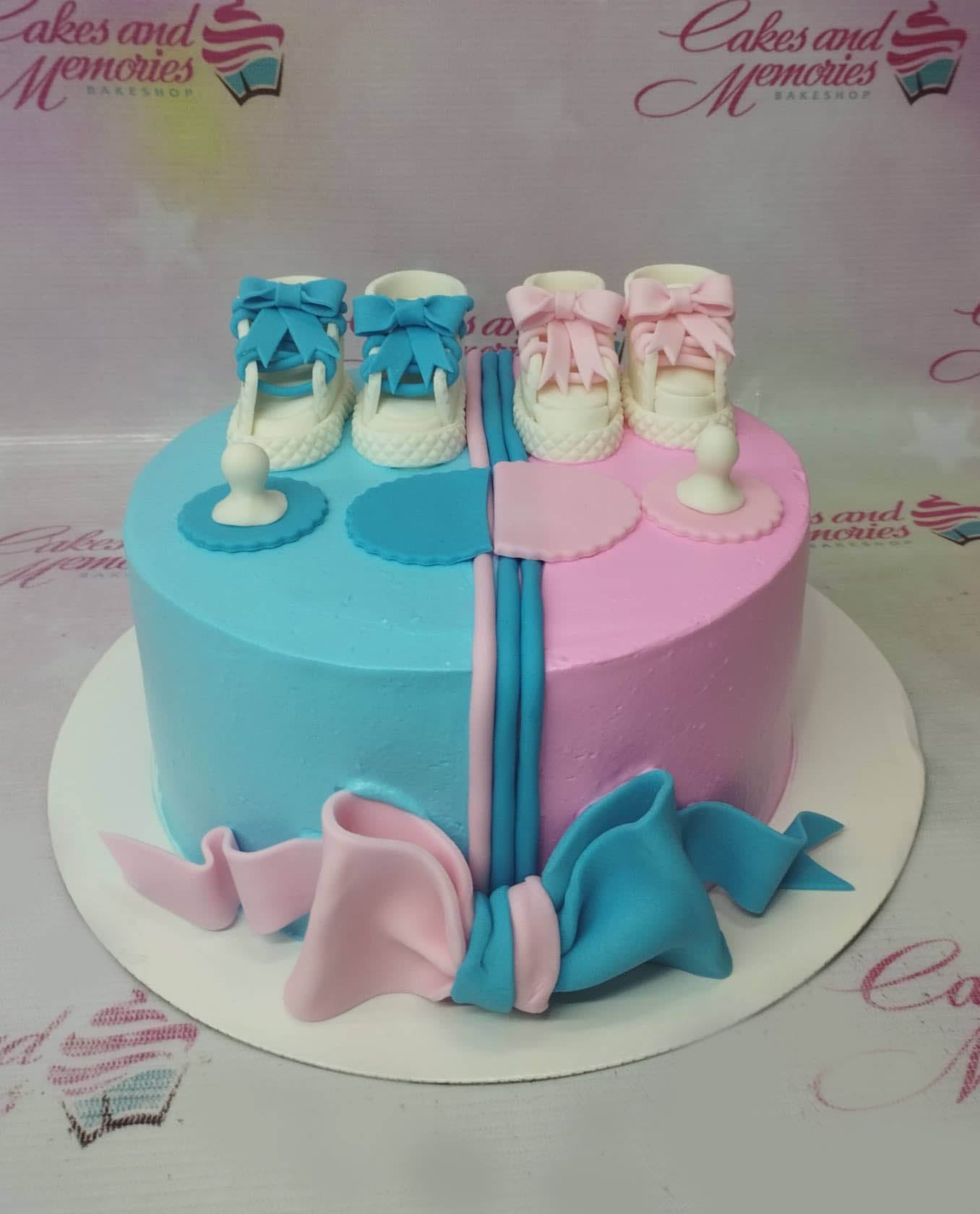 Gender reveal cake with blue and pink icing, fondant baby shoes, pacifiers, and a large bow at the base. Gender reveal cake with blue and pink icing, fondant baby shoes, pacifiers, and a large bow at the base.