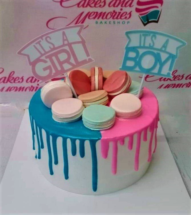 Gender reveal cake with half blue and half pink icing drips, topped with colorful macarons and 'It's a Boy' and 'It's a Girl' toppers. Gender reveal cake with half blue and half pink icing drips, topped with colorful macarons and 'It's a Boy' and 'It's a Girl' toppers.