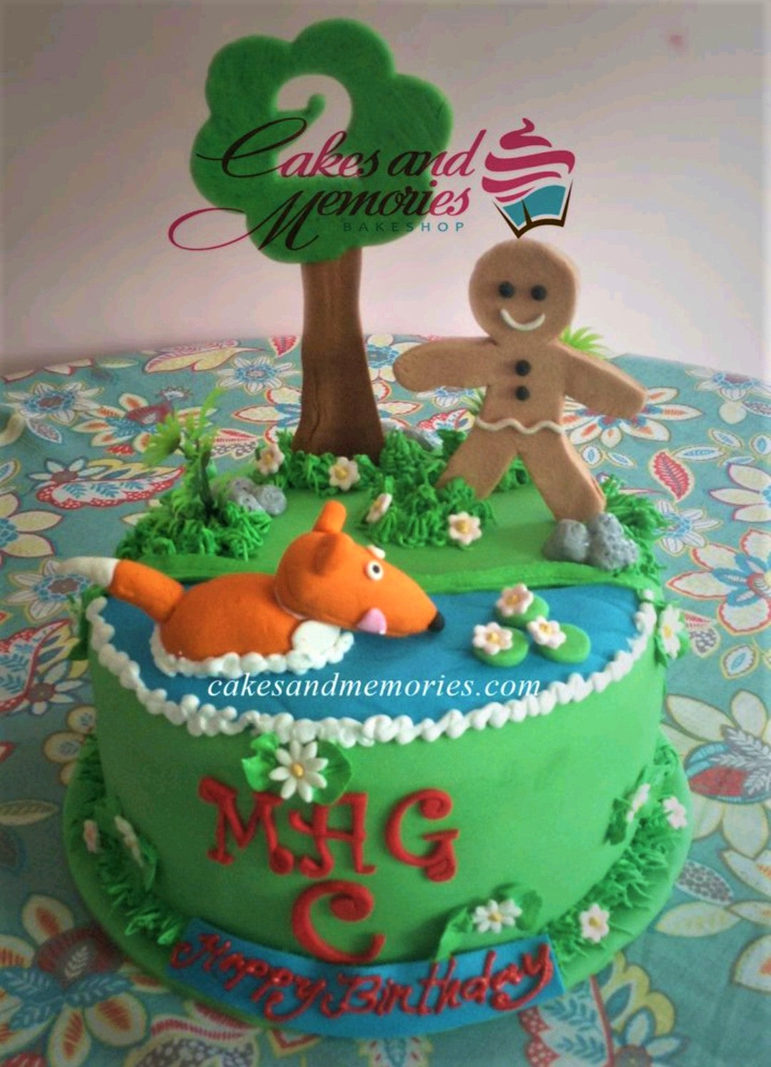 Green fondant cake featuring a gingerbread man, a fox in a pond, and a large tree with a number 2 topper. Green fondant cake featuring a gingerbread man, a fox in a pond, and a large tree with a number 2 topper.