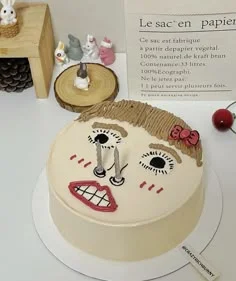 Bento cake with a hand-drawn icing face of a girl with brown hair, a pink bow, and two silver candles as eyes. Bento cake with a hand-drawn icing face of a girl with brown hair, a pink bow, and two silver candles as eyes.