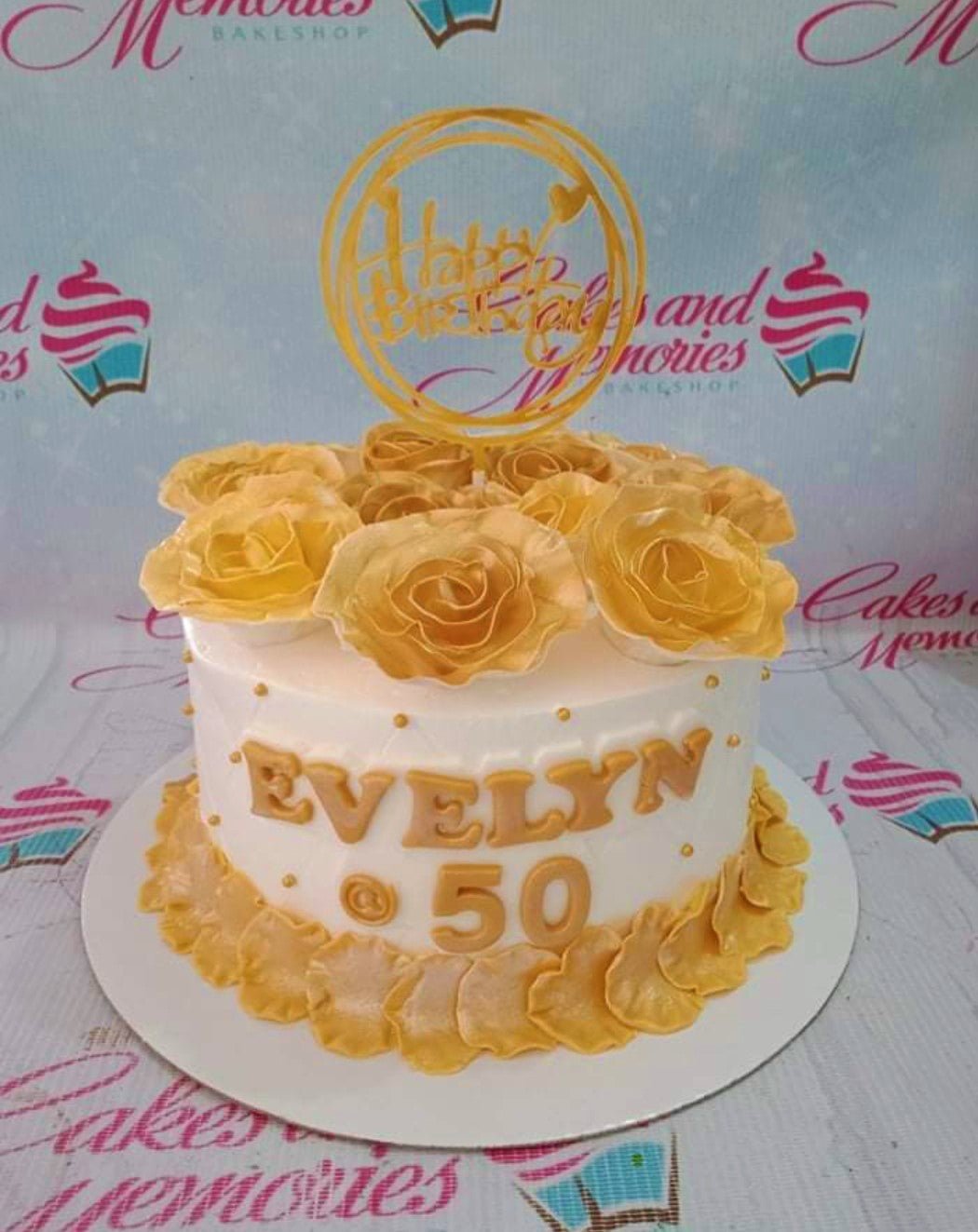 Elegant white 50th birthday cake with gold gumpaste roses, gold name Evelyn, and a gold Happy Birthday topper. Elegant white 50th birthday cake with gold gumpaste roses, gold name Evelyn, and a gold Happy Birthday topper.