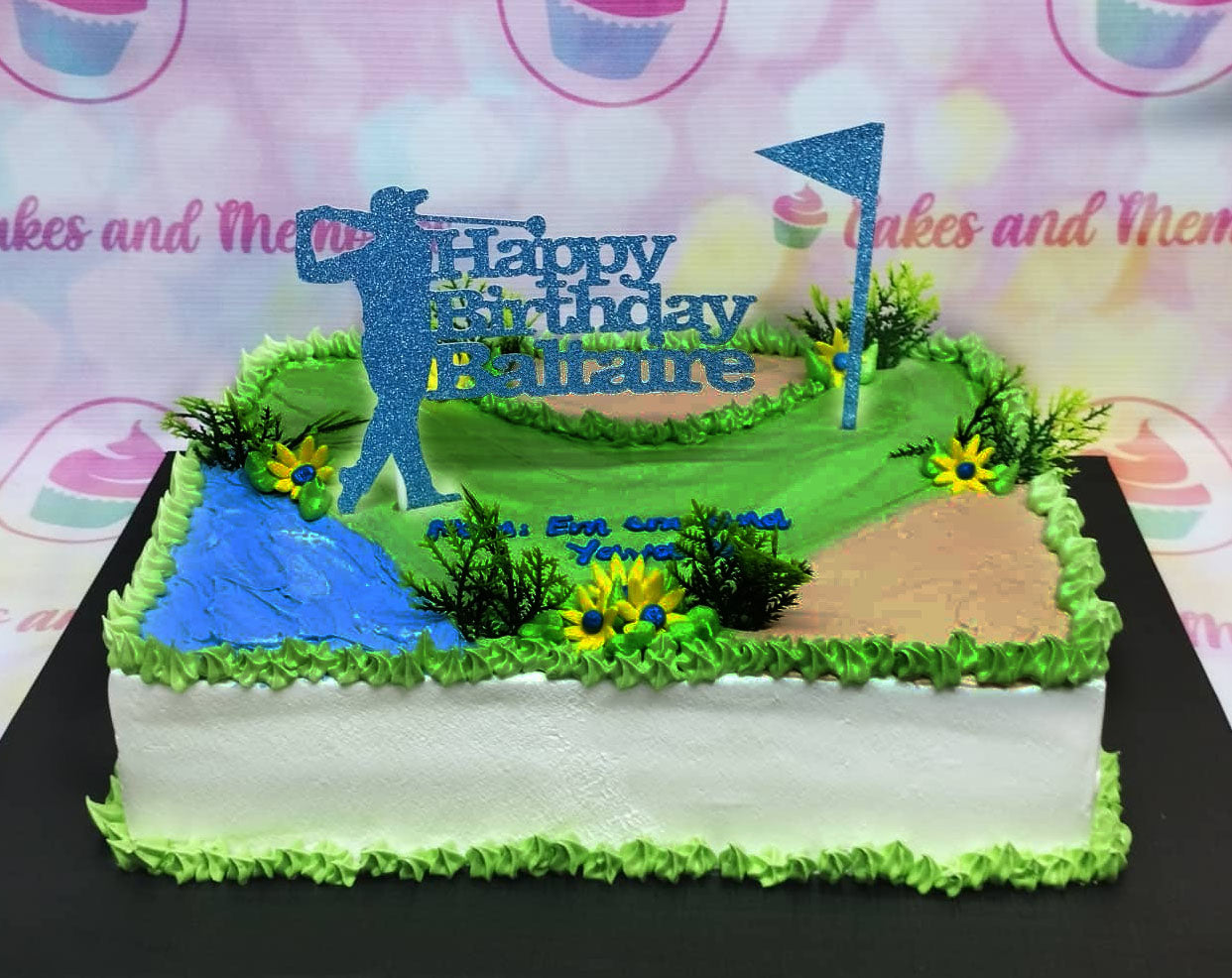 Rectangle golf themed birthday cake with green grass icing, a blue water hazard, sand trap, and a blue glitter golfer topper. Rectangle golf themed birthday cake with green grass icing, a blue water hazard, sand trap, and a blue glitter golfer topper.