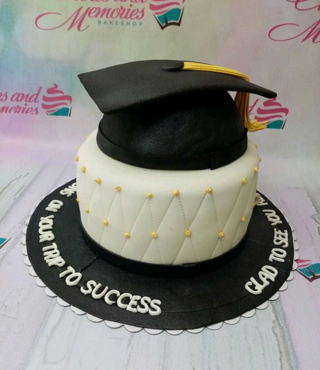 White fondant graduation cake with a black graduation cap topper, yellow tassel, and quilted pattern with gold beads. White fondant graduation cake with a black graduation cap topper, yellow tassel, and quilted pattern with gold beads.