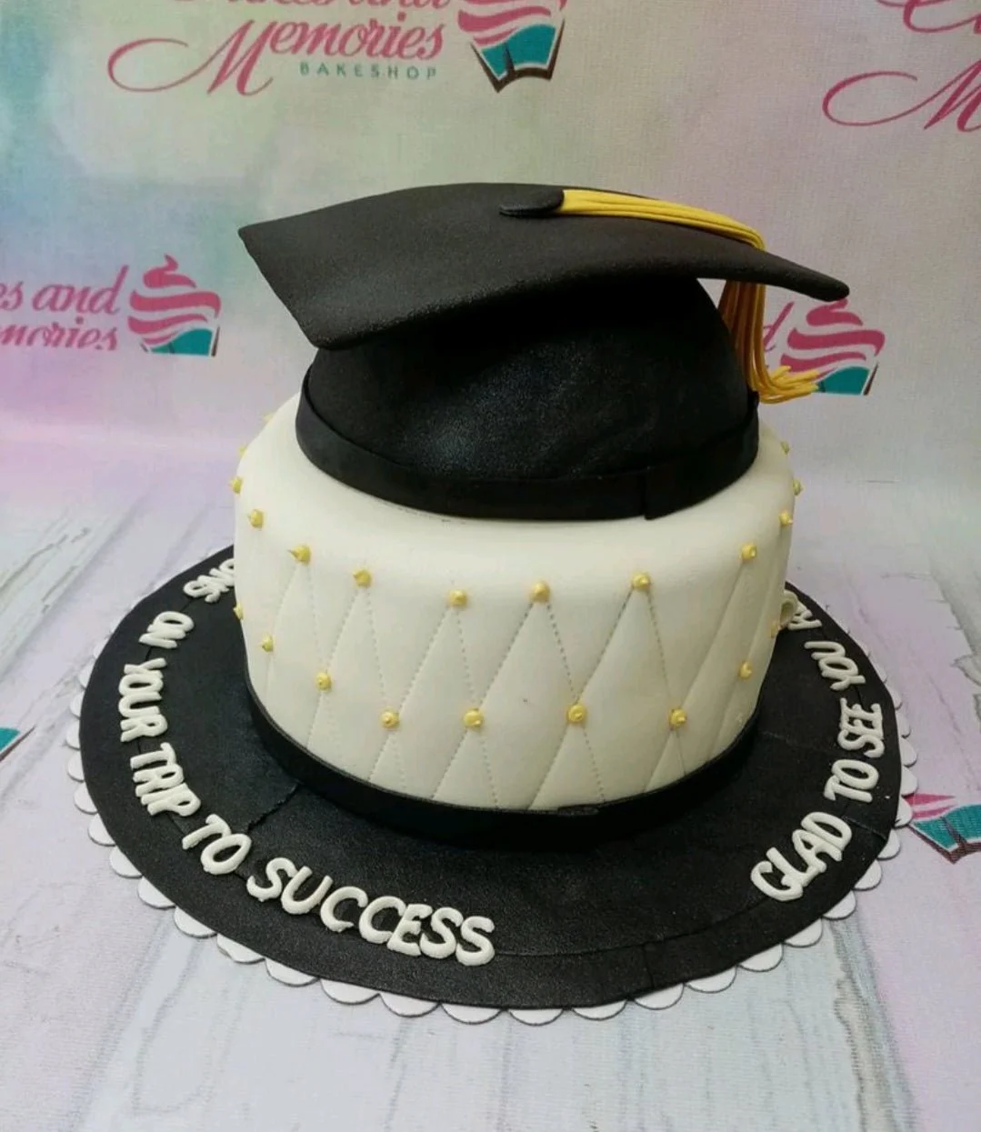Graduation White Cake A white 1 Tier Fondant cake themed around Graduation, featuring a black graduation cap, yellow tassel, and quilted pattern with gold beads.