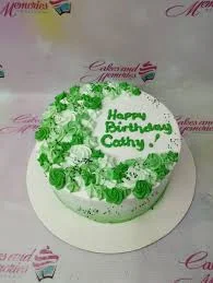 Green birthday cake design — 1 layer soft icing cake in white — with black sprinkles, and custom "Happy Birthday Cathy!" message