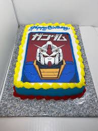 Gundam themed rectangle birthday cake with blue and white icing, yellow borders, and a large Gundam character printout on top. Gundam themed rectangle birthday cake with blue and white icing, yellow borders, and a large Gundam character printout on top.