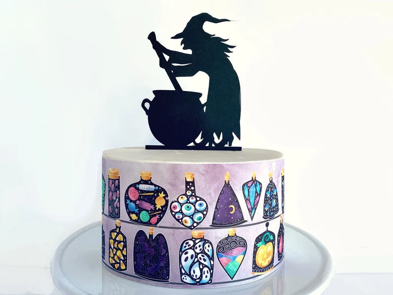Halloween witch cake with a black silhouette topper and a purple side wrap featuring various potion bottles and spooky ingredients. Halloween witch cake with a black silhouette topper and a purple side wrap featuring various potion bottles and spooky ingredients.