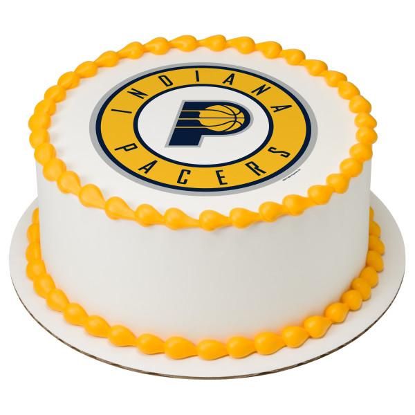 White round Indiana Pacers basketball themed cake with yellow icing borders and a large team logo on top. White round Indiana Pacers basketball themed cake with yellow icing borders and a large team logo on top.