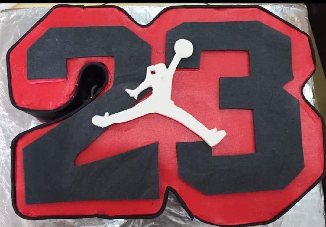 Custom number 23 cake in red and black with a white Jordan jumpman logo on top. Custom number 23 cake in red and black with a white Jordan jumpman logo on top.