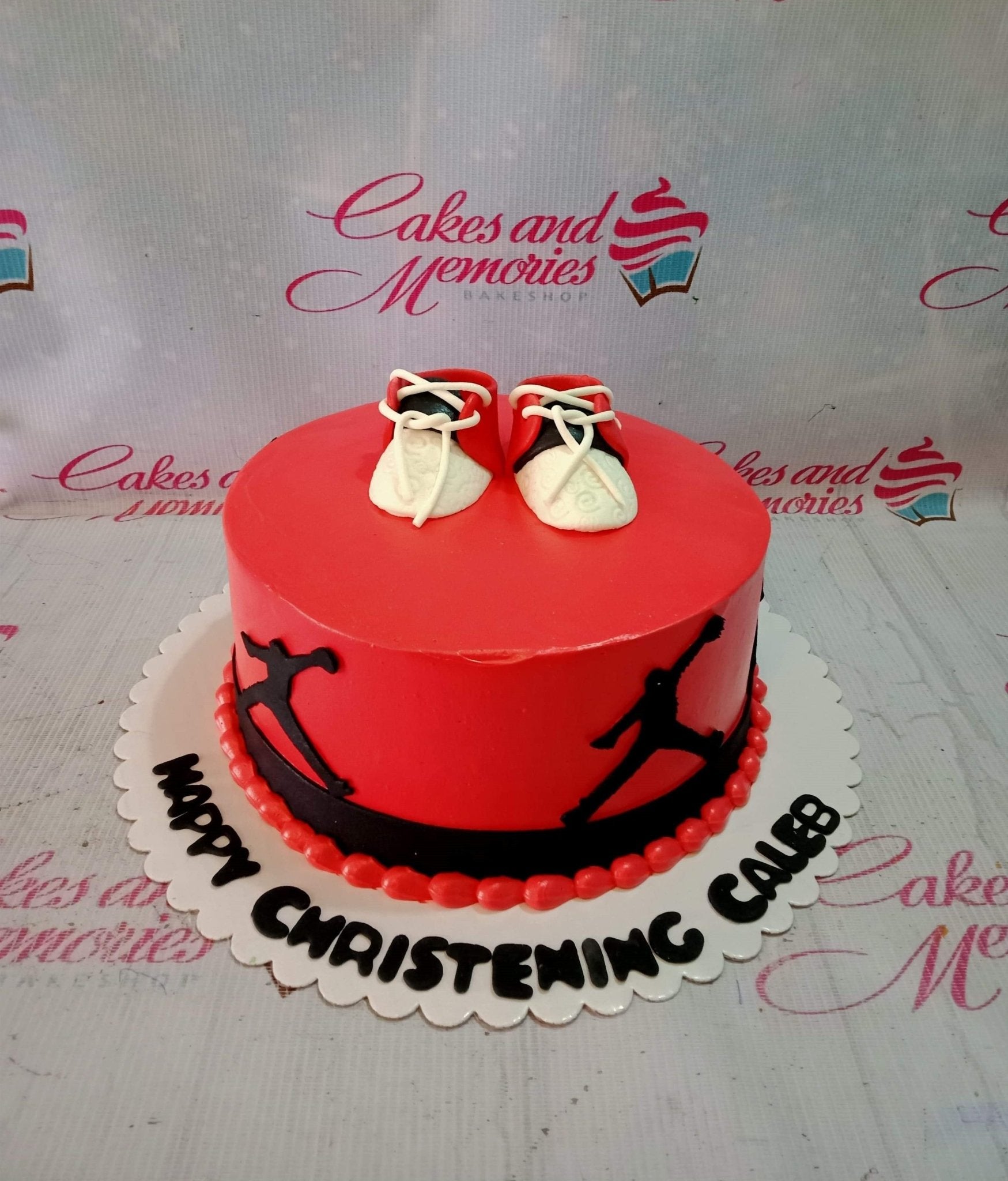 Red and black Nike Jordan themed christening cake with fondant baby sneakers and silhouette toppers. Red and black Nike Jordan themed christening cake with fondant baby sneakers and silhouette toppers.