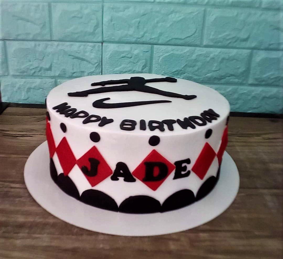 White round cake with black and red diamond patterns, a black silhouette topper, and Happy Birthday Jade message. White round cake with black and red diamond patterns, a black silhouette topper, and Happy Birthday Jade message.
