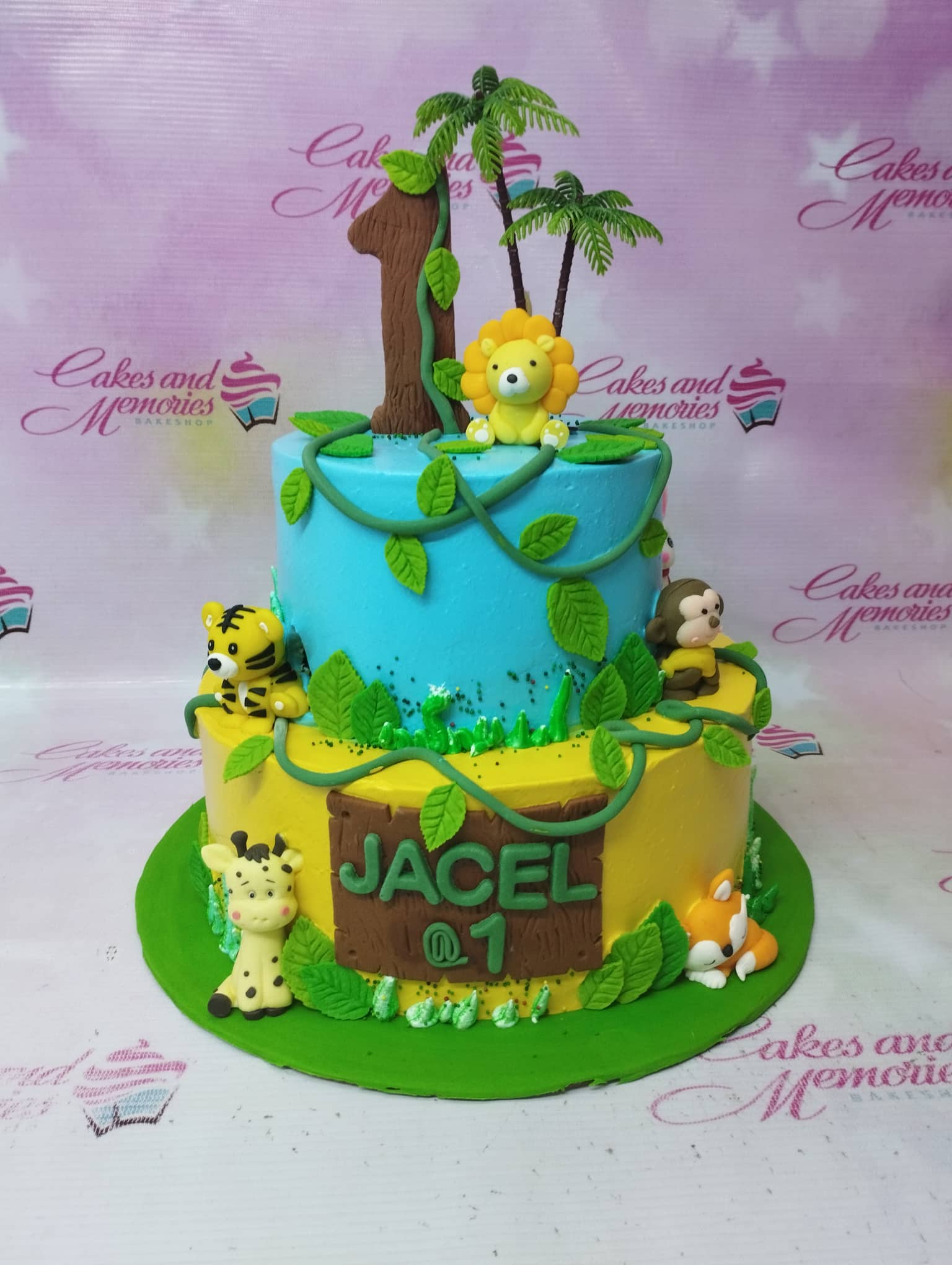 Two-tier jungle safari birthday cake with fondant animals including a lion, tiger, giraffe, monkey, and fox on blue and yellow icing. Two-tier jungle safari birthday cake with fondant animals including a lion, tiger, giraffe, monkey, and fox on blue and yellow icing.