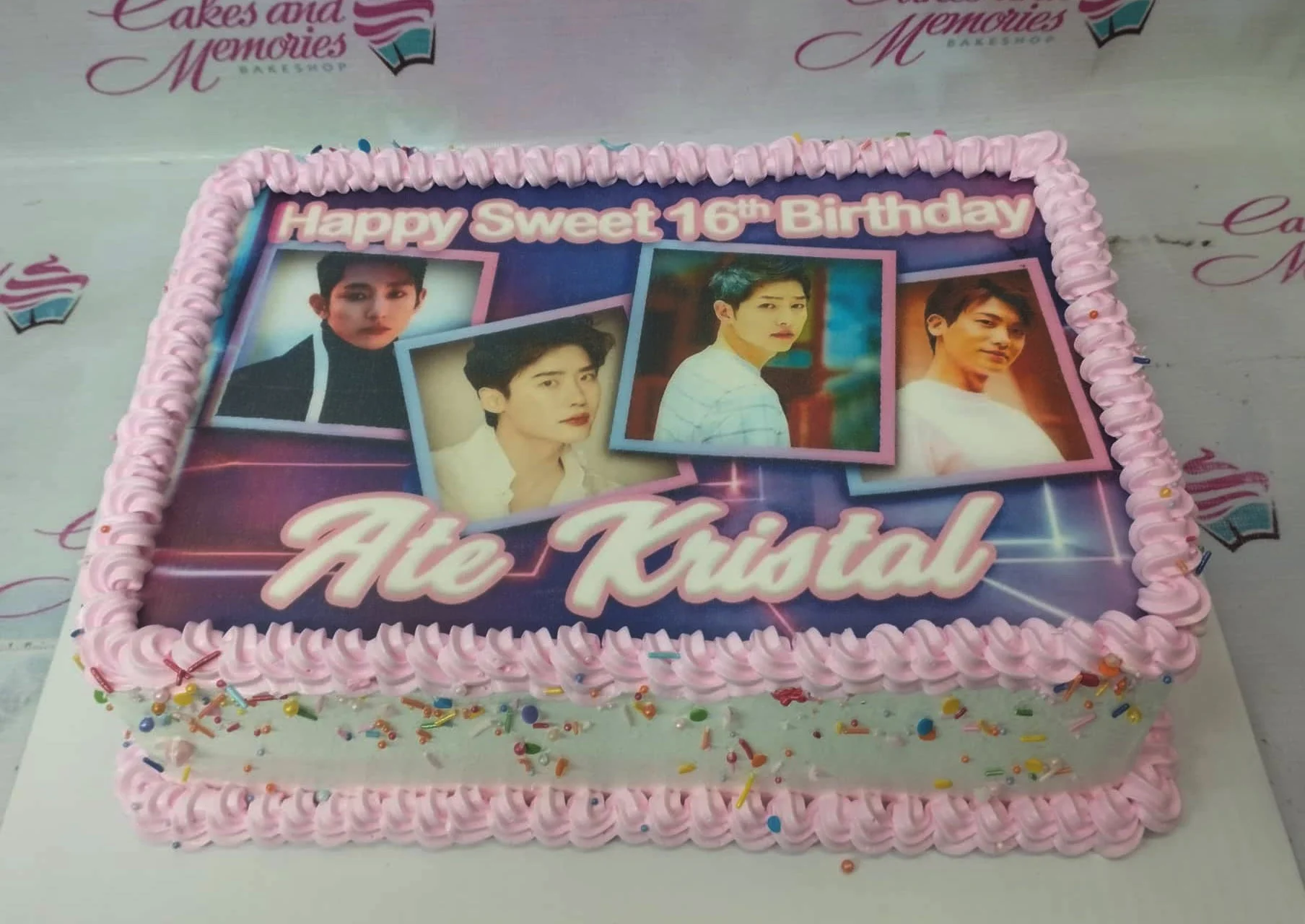 Rectangle K-pop themed birthday cake with pink icing borders, colorful sprinkles, and a large printout featuring Korean actors.