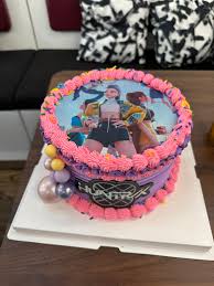 Purple 1-tier cake with a large character printout on top, pink piped icing borders, and metallic decorative balls. Purple 1-tier cake with a large character printout on top, pink piped icing borders, and metallic decorative balls.