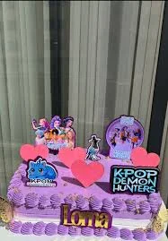 Purple rectangle K-pop Demon Hunters themed cake with pink hearts and character printouts Purple rectangle K-pop Demon Hunters themed cake with pink hearts and character printouts