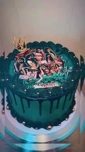 Dark teal green cake with black chocolate drip, gold crown topper, and a large K-pop group printout on top. Dark teal green cake with black chocolate drip, gold crown topper, and a large K-pop group printout on top.
