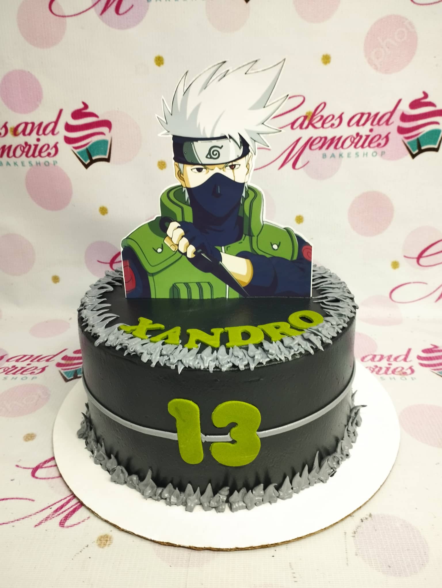 Black Kakashi Hatake Naruto themed cake with grey icing spikes and lime green name and age toppers. Black Kakashi Hatake Naruto themed cake with grey icing spikes and lime green name and age toppers.
