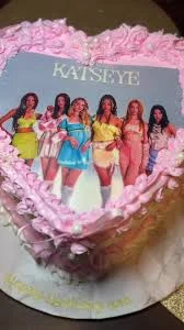 Heart-shaped pink soft-icing cake featuring a Katseye K-pop group printout topper with intricate pink icing ruffles and white pearls. Heart-shaped pink soft-icing cake featuring a Katseye K-pop group printout topper with intricate pink icing ruffles and white pearls.
