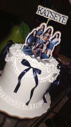 White soft-icing cake with navy blue ribbons and a Katseye K-pop group printout topper. White soft-icing cake with navy blue ribbons and a Katseye K-pop group printout topper.