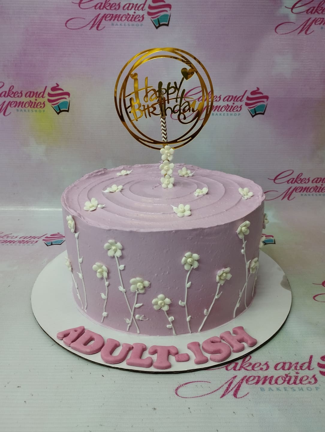 Lavender purple birthday cake with white piped flowers and a gold Happy Birthday topper Lavender purple birthday cake with white piped flowers and a gold Happy Birthday topper