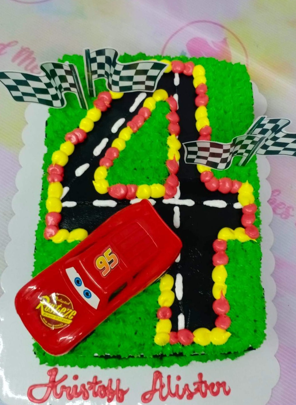 Rectangle Lightning McQueen racing themed cake with a large number 4 road design and checkered flags. Rectangle Lightning McQueen racing themed cake with a large number 4 road design and checkered flags.