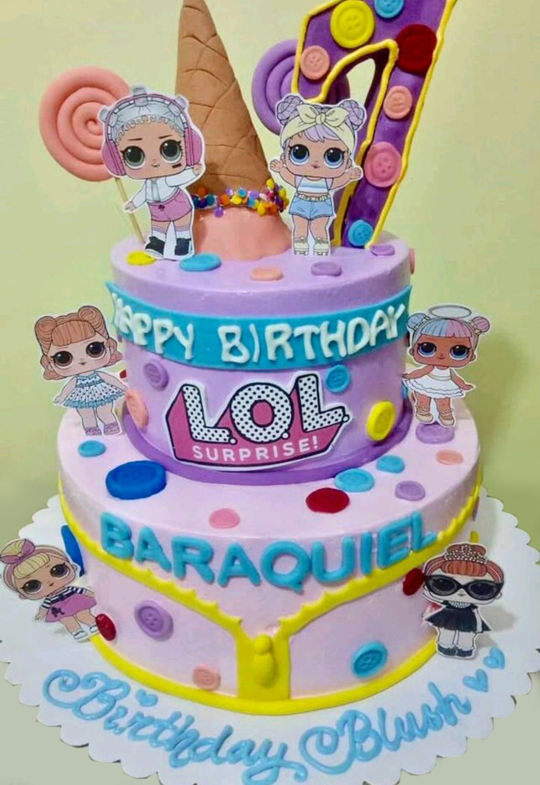 Two-tier purple and pink LOL Surprise themed birthday cake with character printouts, ice cream cone topper, and colorful button decorations. Two-tier purple and pink LOL Surprise themed birthday cake with character printouts, ice cream cone topper, and colorful button decorations.