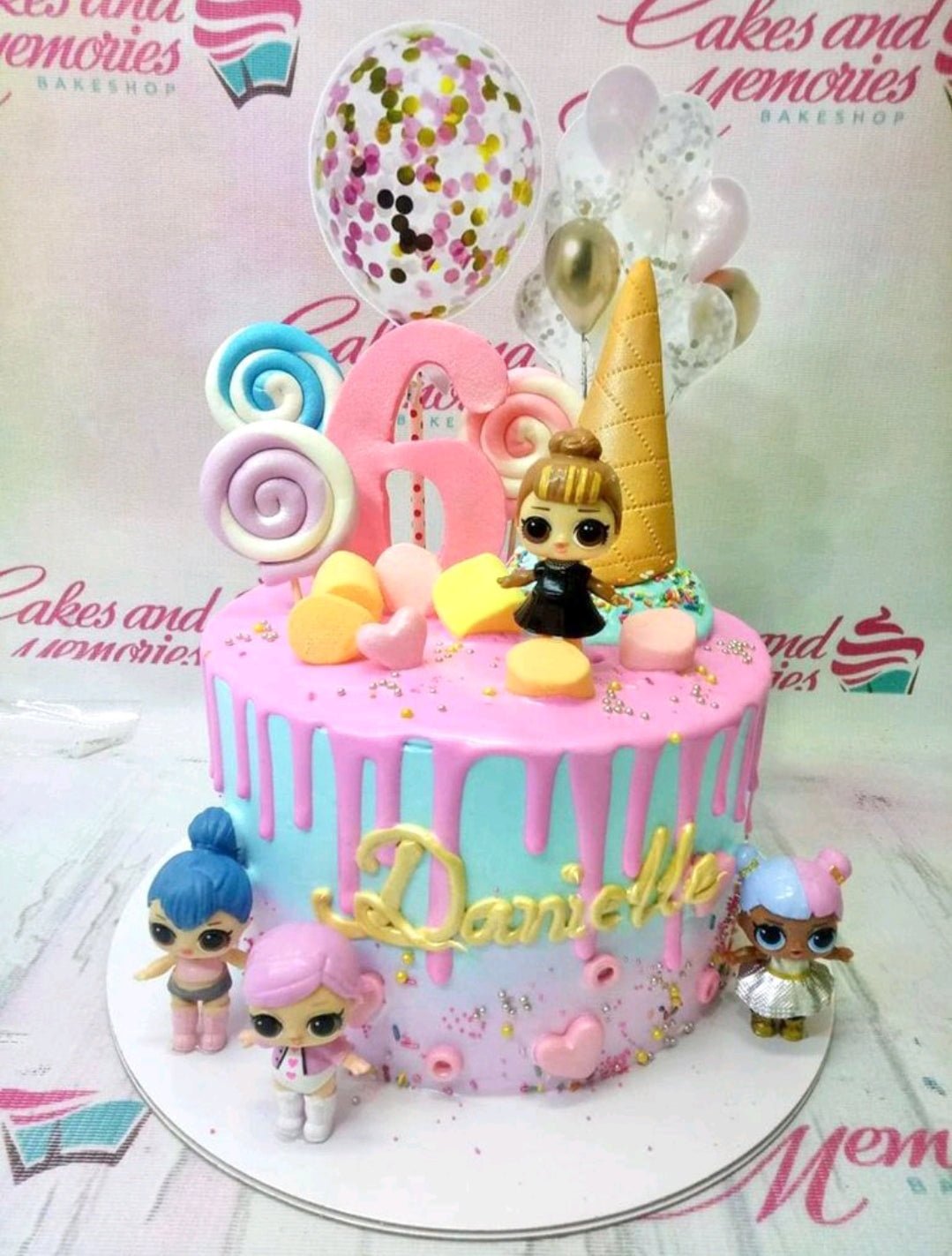 Pink and blue LOL Surprise themed birthday cake with a large pink number 6, LOL dolls, and colorful candy toppers. Pink and blue LOL Surprise themed birthday cake with a large pink number 6, LOL dolls, and colorful candy toppers.