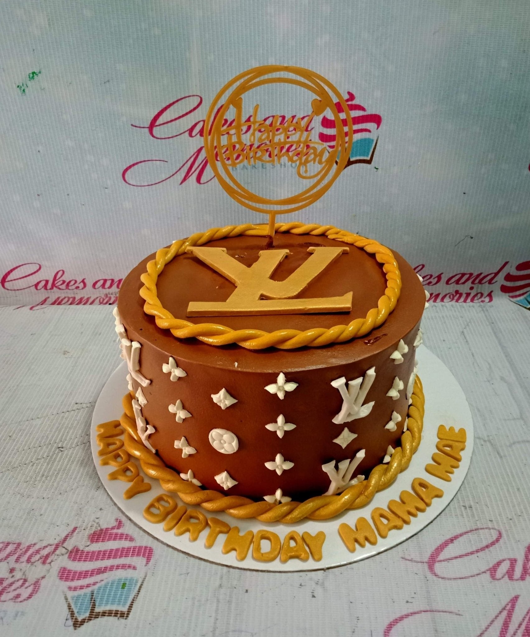 Brown Louis Vuitton themed birthday cake with gold rope borders and white LV monogram patterns. Brown Louis Vuitton themed birthday cake with gold rope borders and white LV monogram patterns.