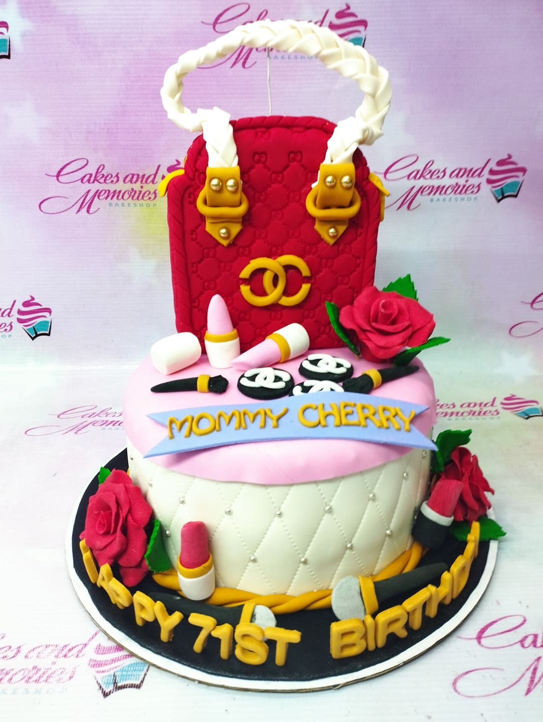 Red and pink luxury handbag and makeup themed two-tier birthday cake with fondant roses and lipstick toppers. Red and pink luxury handbag and makeup themed two-tier birthday cake with fondant roses and lipstick toppers.