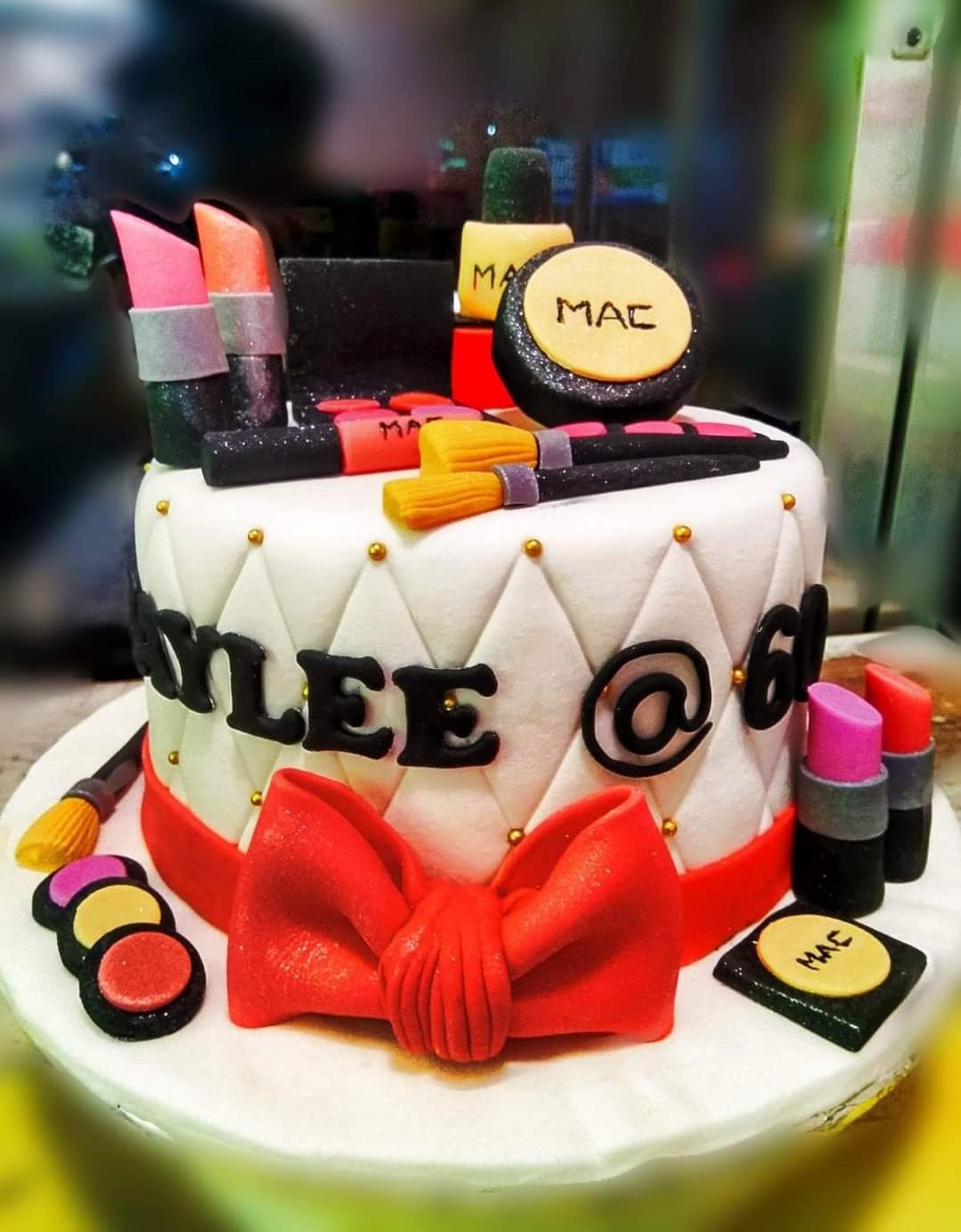 White fondant makeup themed cake with red bow and edible 3D MAC cosmetics toppers including lipstick, brushes, and eyeshadow. White fondant makeup themed cake with red bow and edible 3D MAC cosmetics toppers including lipstick, brushes, and eyeshadow.