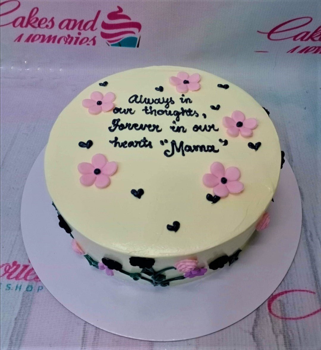 White minimalist round cake with pink fondant flowers and black piped icing message for Mama. White minimalist round cake with pink fondant flowers and black piped icing message for Mama.