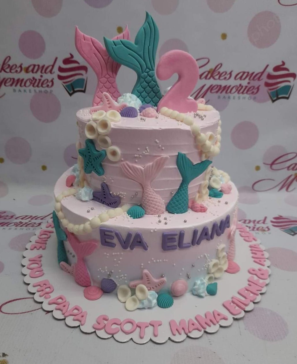 Pink 2-tier mermaid themed birthday cake with fondant mermaid tails, sea shells, and purple gumpaste letters for Eva Eliana. Pink 2-tier mermaid themed birthday cake with fondant mermaid tails, sea shells, and purple gumpaste letters for Eva Eliana.