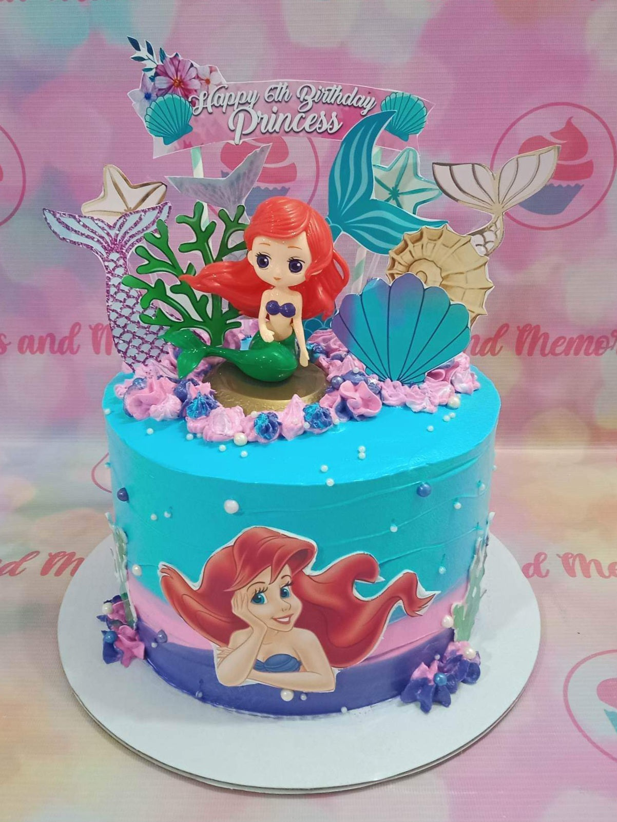 Blue and purple mermaid themed birthday cake with Ariel figurine, mermaid tails, and sea shells. Blue and purple mermaid themed birthday cake with Ariel figurine, mermaid tails, and sea shells.
