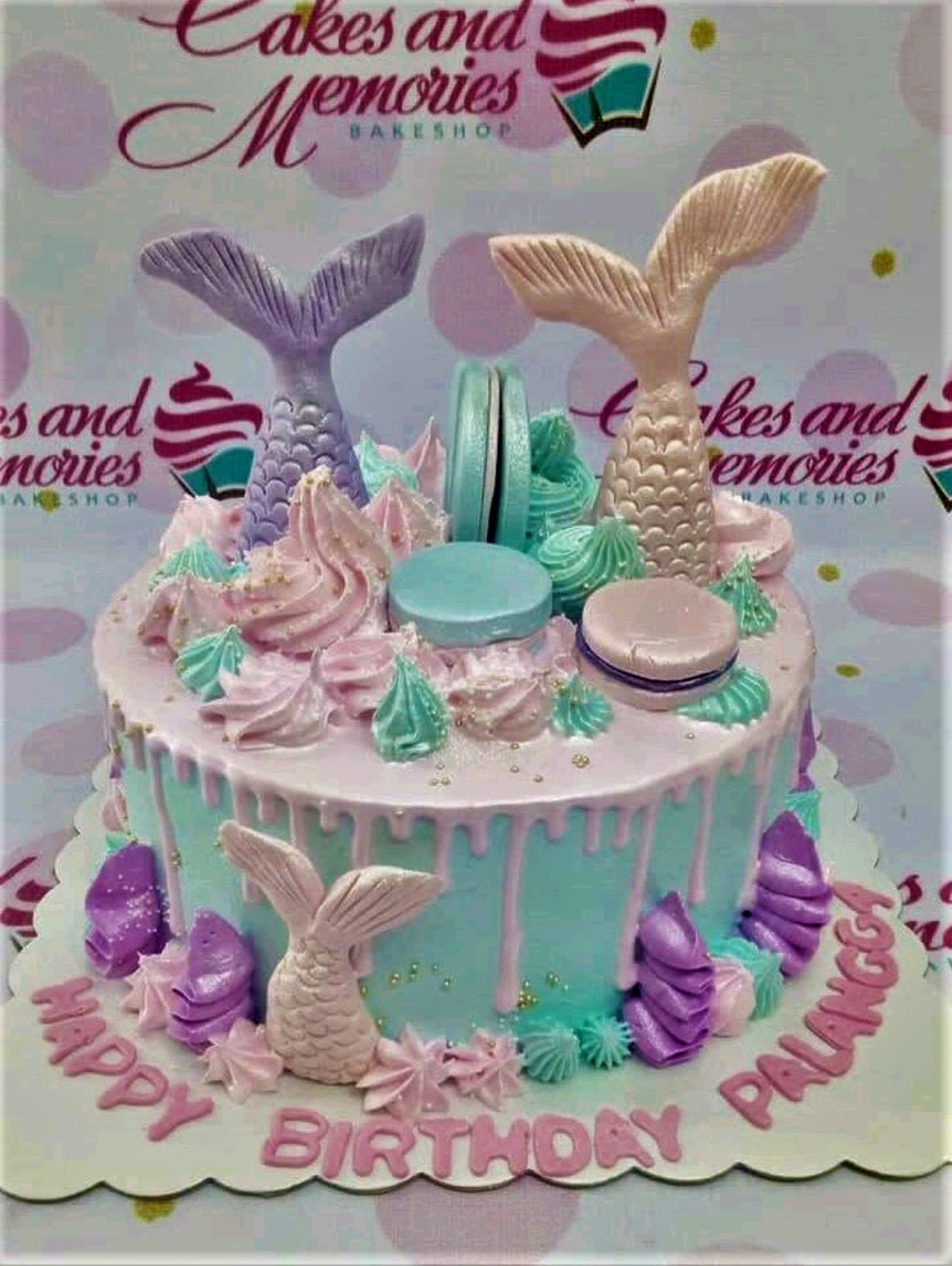 Mermaid themed birthday cake with light blue icing, pink drip, and edible mermaid tails in purple and gold. Mermaid themed birthday cake with light blue icing, pink drip, and edible mermaid tails in purple and gold.