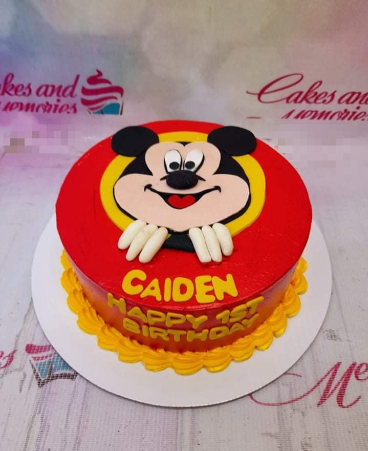 Red Mickey Mouse themed birthday cake with a large Mickey face on top and yellow icing borders. Red Mickey Mouse themed birthday cake with a large Mickey face on top and yellow icing borders.