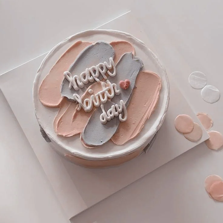 Minimalist bento cake with white icing, peach and lavender palette knife strokes, and a white piped Happy Birthday message. Minimalist bento cake with white icing, peach and lavender palette knife strokes, and a white piped Happy Birthday message.