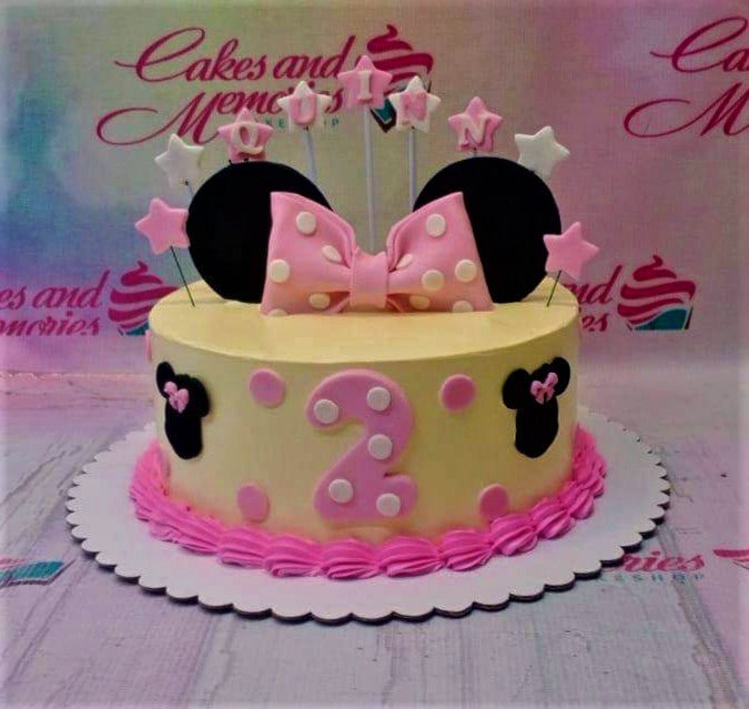 Minnie Mouse themed birthday cake with pink polka dot bow, black ears, and a pink number 2 on light yellow icing. Minnie Mouse themed birthday cake with pink polka dot bow, black ears, and a pink number 2 on light yellow icing.