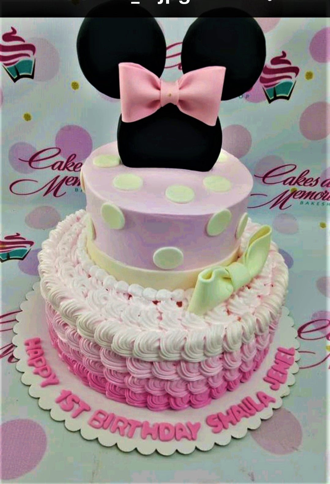 Two-tier Minnie Mouse themed birthday cake with pink ombre icing rosettes and a large black fondant Minnie head topper with a pink bow. Two-tier Minnie Mouse themed birthday cake with pink ombre icing rosettes and a large black fondant Minnie head topper with a pink bow.