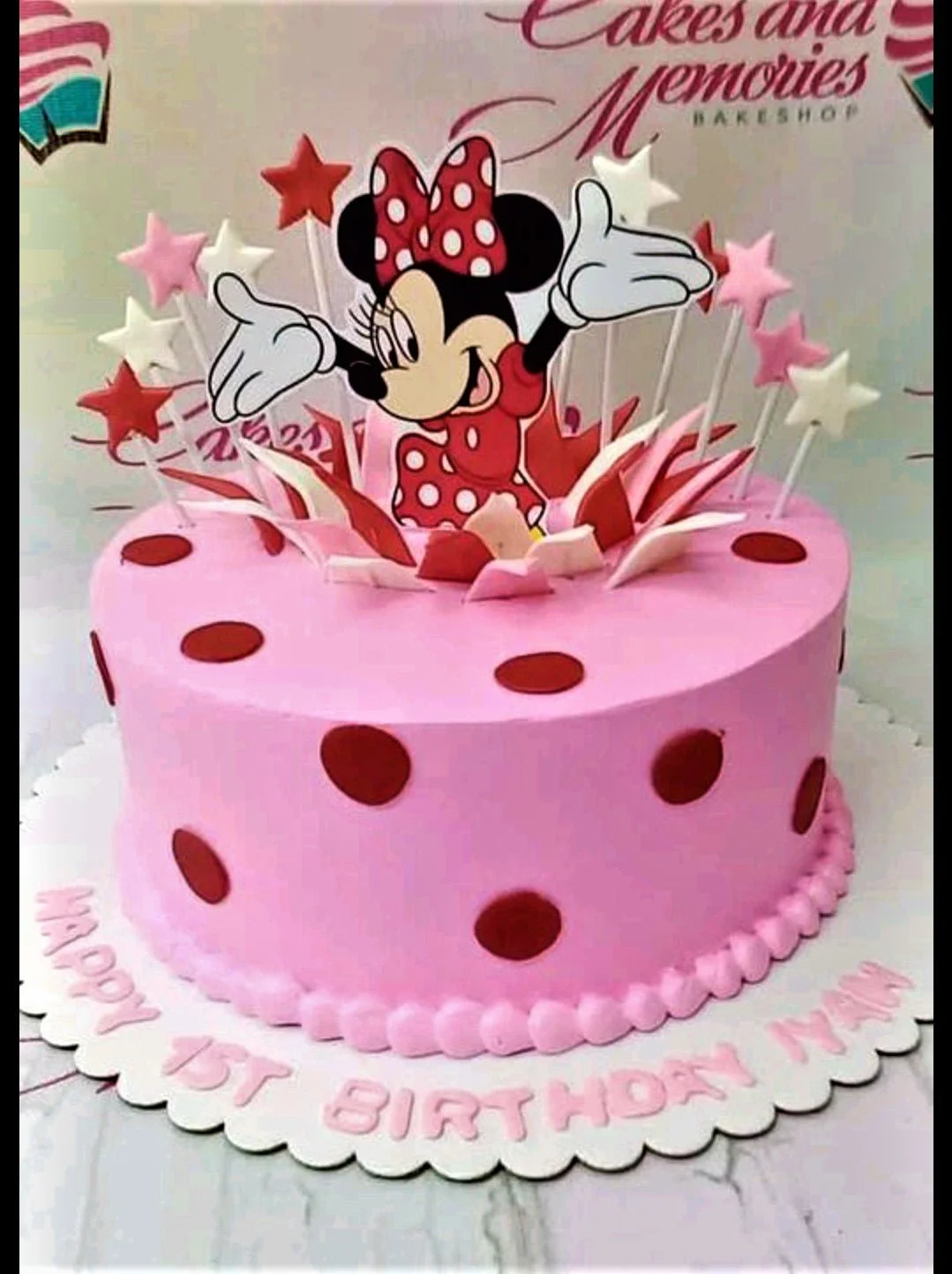 Pink Minnie Mouse birthday cake with red polka dots and star toppers