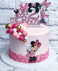 Pink Minnie Mouse birthday cake with a glittery number two topper and a cluster of pink, white, and gold balloon-style spheres. Pink Minnie Mouse birthday cake with a glittery number two topper and a cluster of pink, white, and gold balloon-style spheres.
