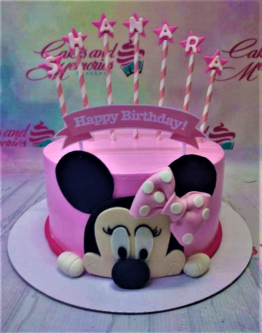 Pink Minnie Mouse themed birthday cake with a large fondant Minnie face and pink star toppers on striped sticks. Pink Minnie Mouse themed birthday cake with a large fondant Minnie face and pink star toppers on striped sticks.